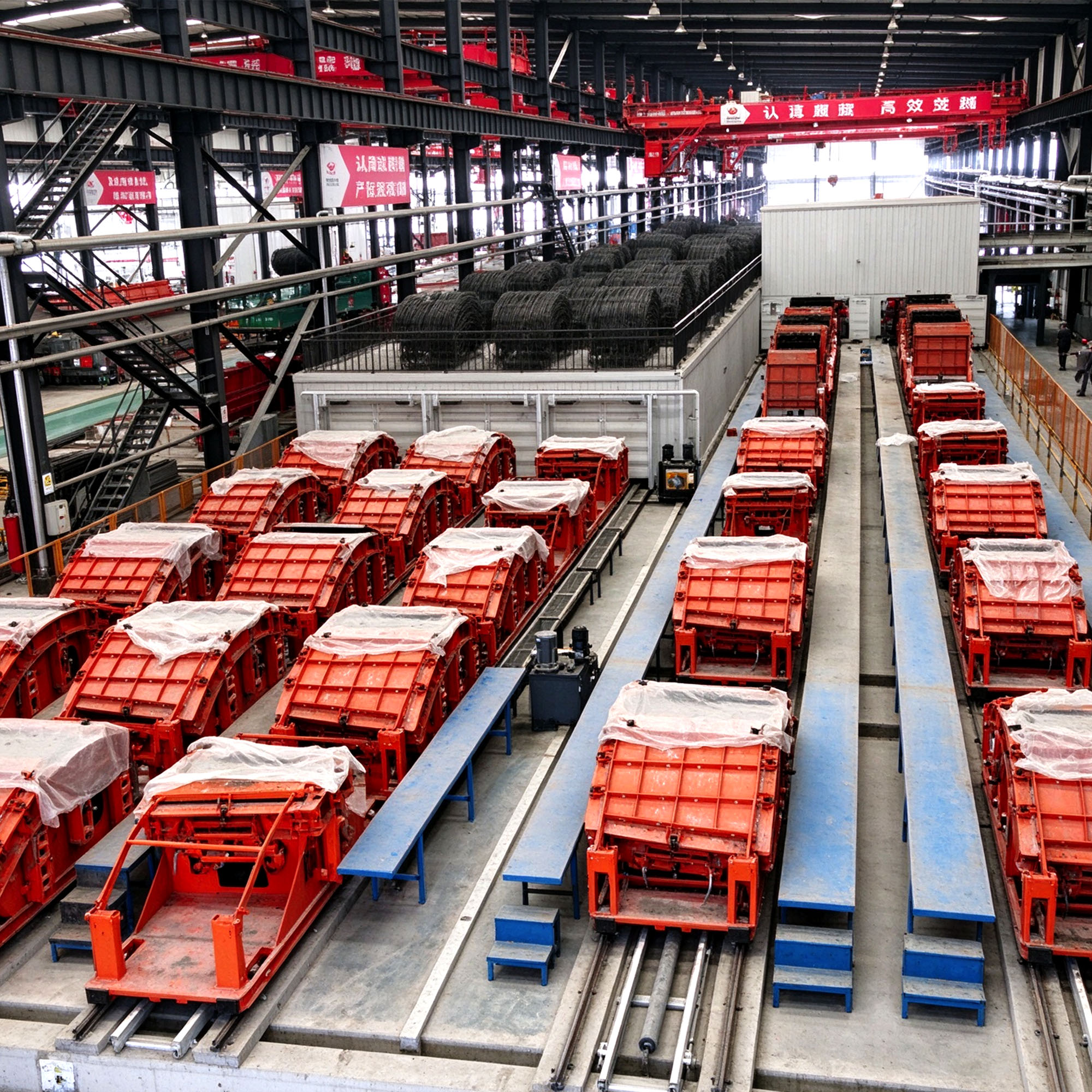 Rows of red segment moulds on transfer tracks in a segment production hall